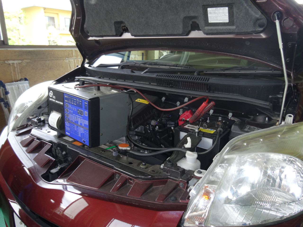 ボンネットが開けられ、バッテリーが接続された車のエンジンルーム