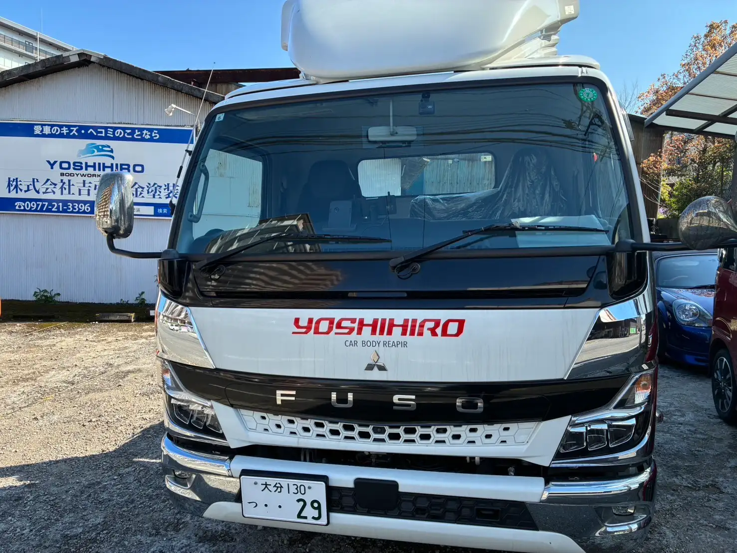 吉弘鈑金塗装のロゴが入った白い積載車